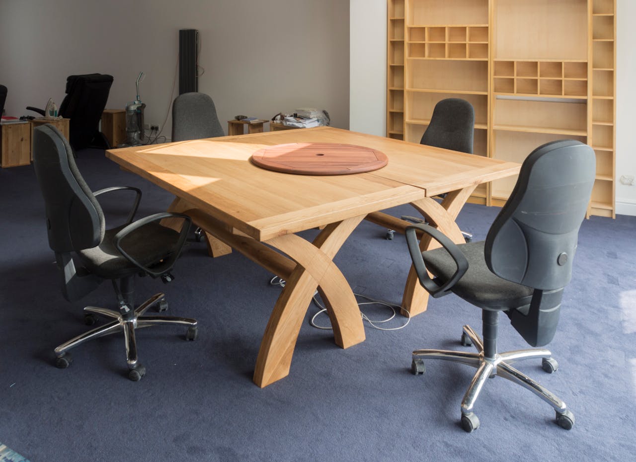 Contemporary office meeting room featuring a unique wooden table design and ergonomic chairs.